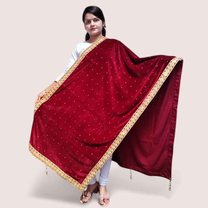 A woman posing in a maroon velvet shawl with detailed gold work, draped over her shoulders.